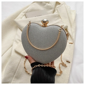 Macro shot of silver heart evening clutch with gold metal frame and jewel clasp