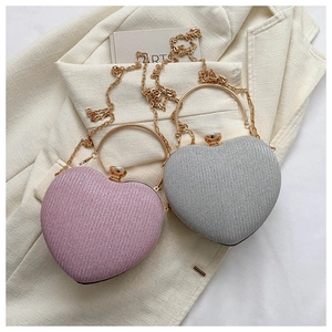 Detail of heart-shaped evening bags in pink and silver with gold ring handles