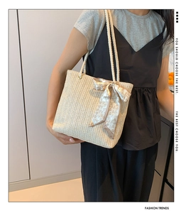 Detail of woven straw tote bag with braided rope handles and heart pattern scarf
