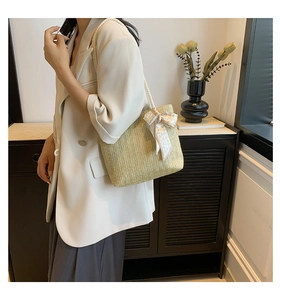 Detail of straw woven tote bag featuring decorative white heart print silk scarf bow