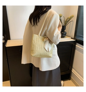 Detail of straw woven tote bag featuring white rope handles and a heart pattern silk scarf