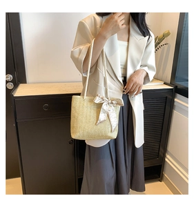 Detail of hand-woven straw tote with elegant heart-print scarf wrap on handle