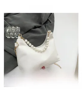 Detailed shot of white crescent bag with pearl handle and golden chain strap