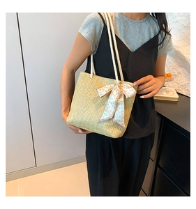 Detail of hand-woven beige straw tote with cotton rope handles and pink heart silk scarf
