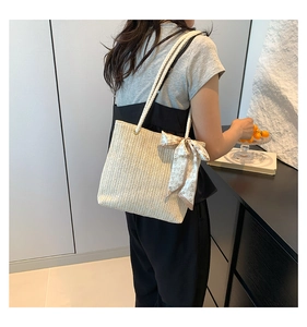 Detail of woven straw tote bag featuring silk scarf bow accent and heart patterns