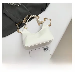Detailed view of white faux leather bag with pearl and gold metal chain strap