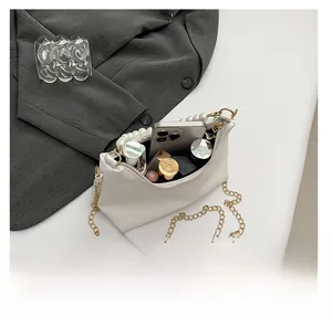 Detail showing white bucket bag interior holding a smartphone and various lipsticks