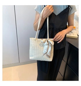 Detail shot of straw tote bag featuring woven V-texture and heart pattern ribbon bow