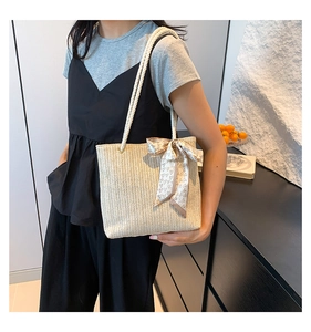 Straw tote bag with silk scarf detail shown on shoulder for size and style reference