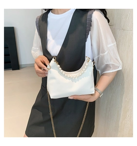 Close-up of crescent handbag with pearl bead handle and gold chain shoulder strap