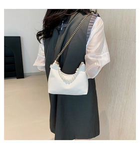 Detail of white PU bucket bag with large pearl handle and gold chain strap on model
