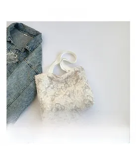 Detailed close-up of white lace tote bag with butterfly embroidery on blue denim