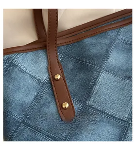 Close-up of blue denim plaid tote with brown leather handles and gold rivet details