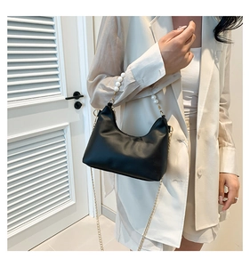 Detailed shot of crescent underarm bag with white pearl handle and gold chain strap