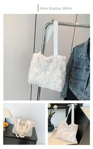 Detail of white canvas tote bag featuring textured 3D butterfly embroidery and wide strap