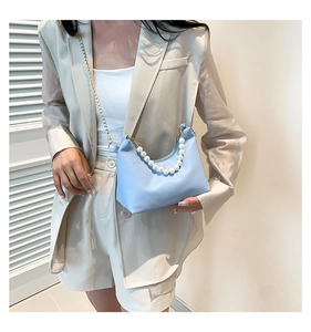 Detail of light blue pearl chain shoulder bag worn with a beige summer blazer