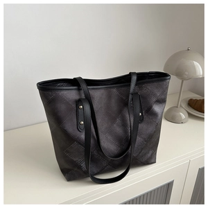 Detail of the large capacity tote bag with dark textured pattern and golden metal rivets