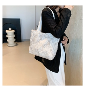 Close-up of white shoulder tote bag featuring textured butterfly patterns and long strap