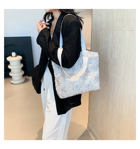 Detailed side view of white plush tote bag with grey butterfly patterns worn by a model