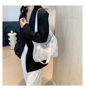 Close-up of white plush tote bag featuring grey butterfly embroidery and wide shoulder strap
