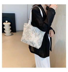Detailed texture of white lace tote bag with grey butterfly patterns and canvas handles