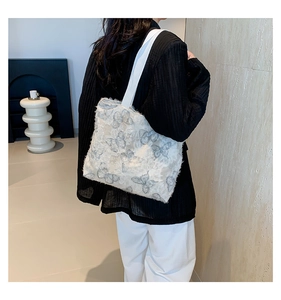 Detailed shot of white butterfly tote bag with feather tassels on female model