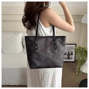 Detail of grey vintage denim tote bag with metal rivets and long black shoulder straps