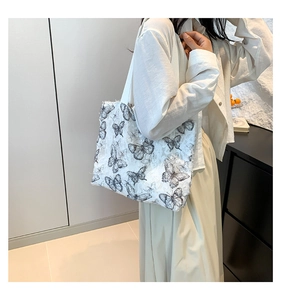 Detailed view of the frayed edge and black butterfly lace embroidery on white tote bag