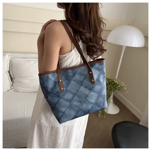 Detail of blue and white denim patchwork tote bag with brown leather handles and gold rivets