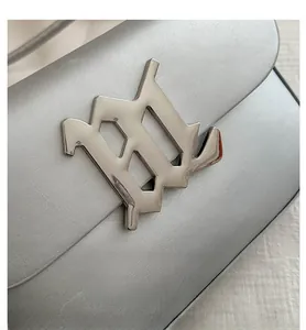 Close-up of silver leather handbag with metallic M-shaped buckle and fine stitching detail