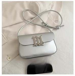 Silver metallic crossbody bag size comparison with a smartphone on a soft textured background
