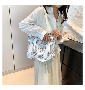 Detail of white canvas tote with gray butterfly embroidery and fringe texture edges