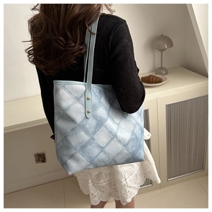 Detail of light blue checkered tote bag with gold rivets and slim shoulder straps