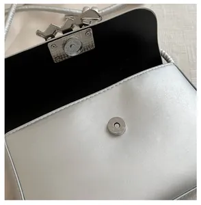 Detail of silver PU leather crossbody bag featuring a shiny metallic magnetic buckle closure