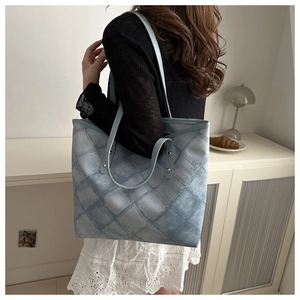 Close-up of light blue quilted tote bag with diamond pattern and metal rivets detail