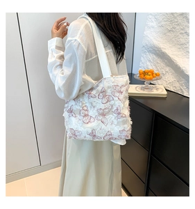 Detail of white tote bag featuring 3D pink butterfly embroidery and fringed texture