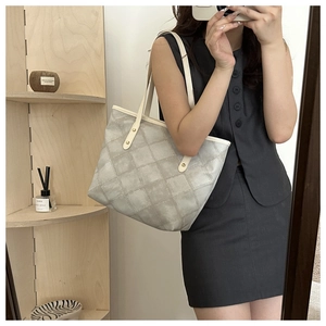 Detail of grey quilted tote bag with cream handles and elegant gold rivet hardware