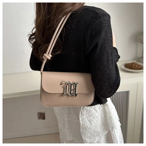 Detail of minimalist beige flap crossbody bag with silver gothic logo and knotted strap