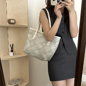 Minimalist grey quilted tote bag with white straps shown in a chic mirror selfie view