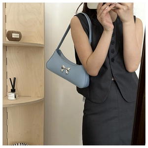 Detail of light blue baguette bag with silver metal bow and matte PU leather finish