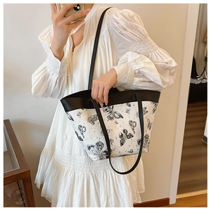 Detail of a large white tote bag featuring black butterfly and celestial star patterns