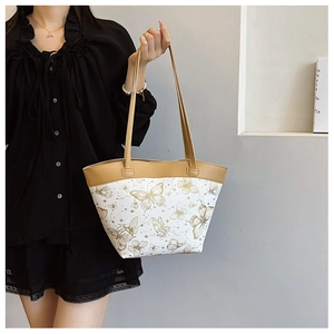 Detail of elegant bucket bag featuring butterfly print and tan leather shoulder strap