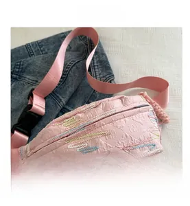 Détail d'un sac de poitrine en jacquard rose avec broderie vagues et sangle en nylon