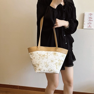Elegant white tote bag with gold butterfly print and brown straps shown on a model