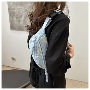 Détail du sac de poitrine bleu clair matelassé avec broderies et tirette de zip tissée