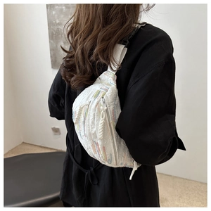 Détail du sac bandoulière blanc avec broderie arc-en-ciel et texture gaufrée chic