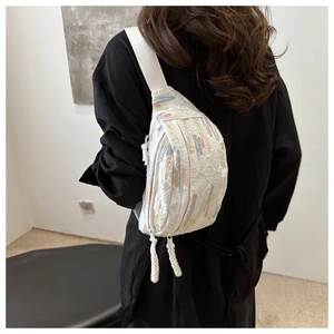 Détail du sac bandoulière matelassé blanc avec broderies colorées et tirette de zip
