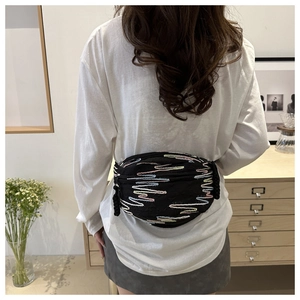 Détail de broderie arc-en-ciel colorée sur un sac banane noir avec tirette de zip tissée