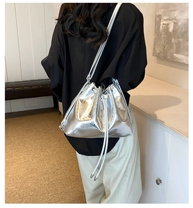 Detail view of the silver metallic bucket bag with drawstring closure and slim shoulder strap