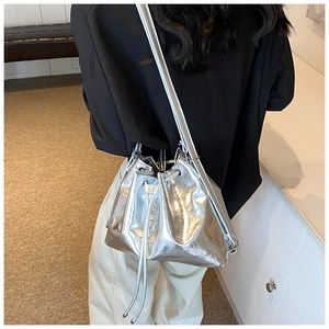 Detailaufnahme einer metallisch silbernen Beuteltasche mit Kordelzug am Modell